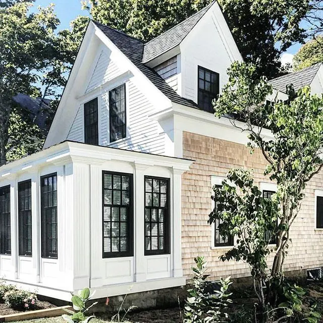 A white two story house from the outside with trees in the back